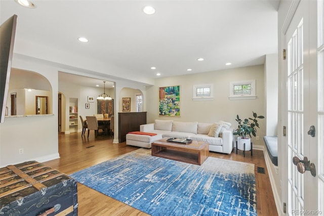living room featuring recessed lighting, arched walkways, baseboards, and wood finished floors