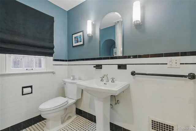 bathroom featuring visible vents, a wainscoted wall, toilet, and tile walls
