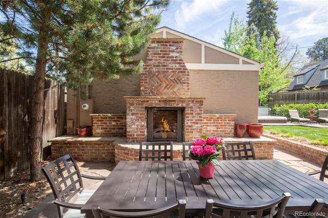 view of patio / terrace with fence, an outdoor brick fireplace, and outdoor dining space