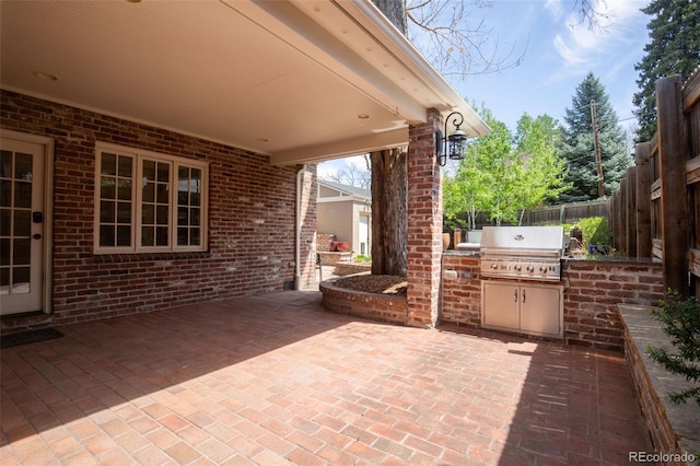 view of patio featuring area for grilling, an outdoor kitchen, and fence
