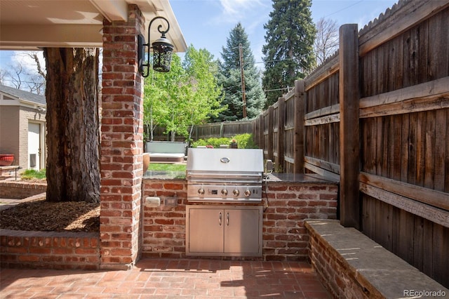 view of patio / terrace with exterior kitchen, fence, and a grill