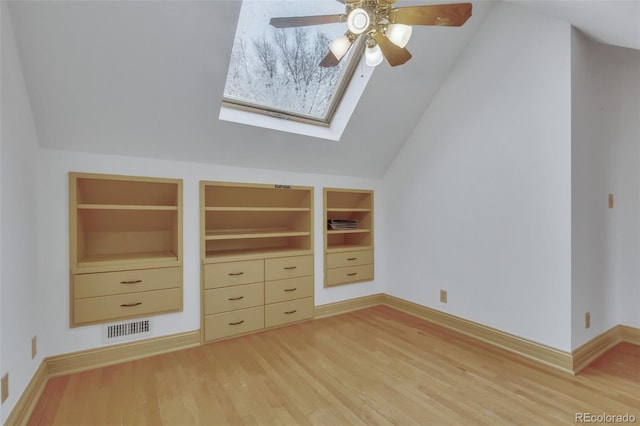 unfurnished bedroom featuring baseboards, visible vents, wood finished floors, and lofted ceiling with skylight