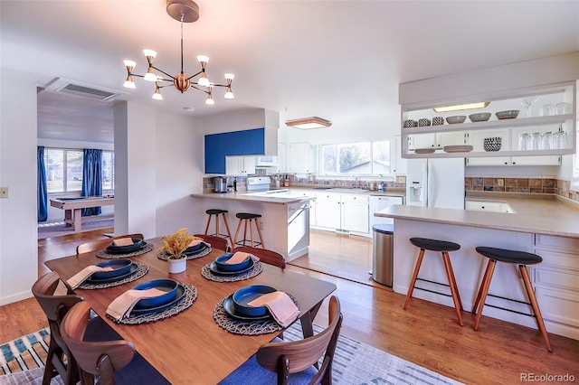 dining room featuring sink, light hardwood / wood-style flooring, and a chandelier