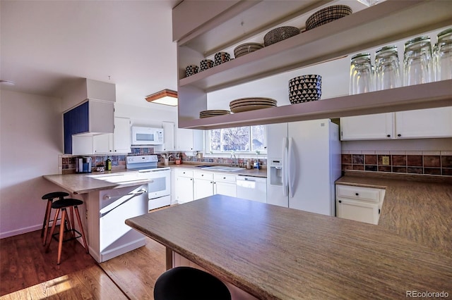 kitchen featuring white cabinetry, white appliances, kitchen peninsula, dark hardwood / wood-style flooring, and sink