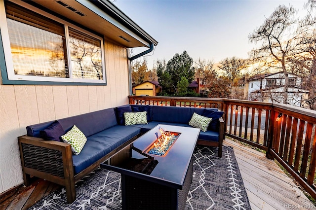 deck at dusk featuring an outdoor living space with a fire pit