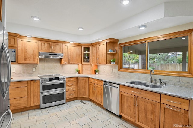7882 S Valentia Way, Centennial, CO 80112 - kitchen with appliances with stainless steel finishes, a sink, under cabinet range hood, decorative backsplash, and brown cabinetry