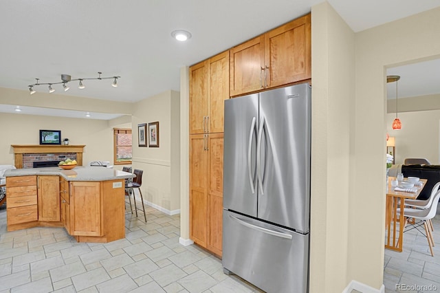 7882 S Valentia Way, Centennial, CO 80112 - kitchen featuring freestanding refrigerator, open floor plan, light countertops, baseboards, and a brick fireplace