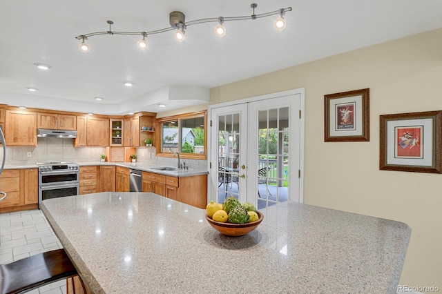 7882 S Valentia Way, Centennial, CO 80112 - kitchen featuring appliances with stainless steel finishes, french doors, a sink, under cabinet range hood, and light stone counters
