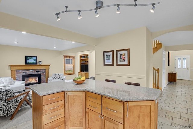7882 S Valentia Way, Centennial, CO 80112 - kitchen with open floor plan, arched walkways, a brick fireplace, light stone countertops, and recessed lighting