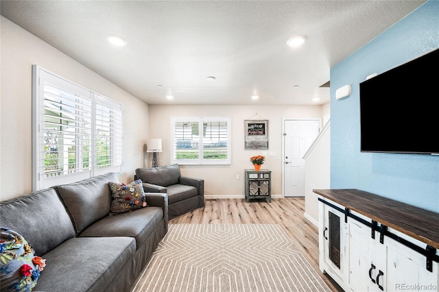 living room with a textured ceiling and light hardwood / wood-style flooring