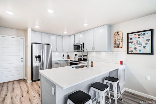 kitchen with a breakfast bar, kitchen peninsula, backsplash, and appliances with stainless steel finishes