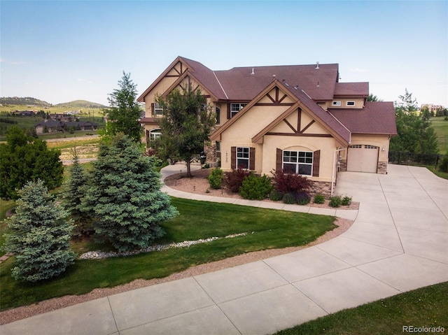 19735 Knights Xing, Monument, CO 80132 - tudor home featuring stucco siding, stone siding, concrete driveway, an attached garage, and a front lawn
