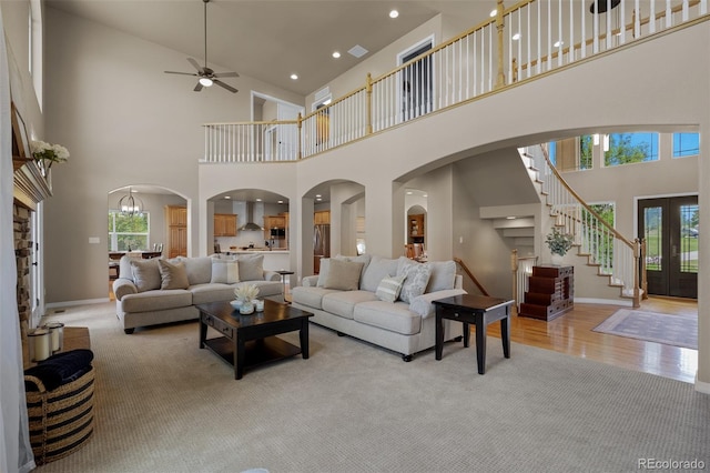 19735 Knights Xing, Monument, CO 80132 - carpeted living area with a high ceiling, a ceiling fan, stairs, arched walkways, and wood finished floors