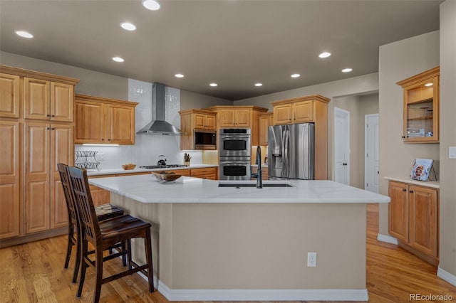 19735 Knights Xing, Monument, CO 80132 - kitchen with appliances with stainless steel finishes, wall chimney range hood, a large island with sink, light wood-style flooring, and recessed lighting