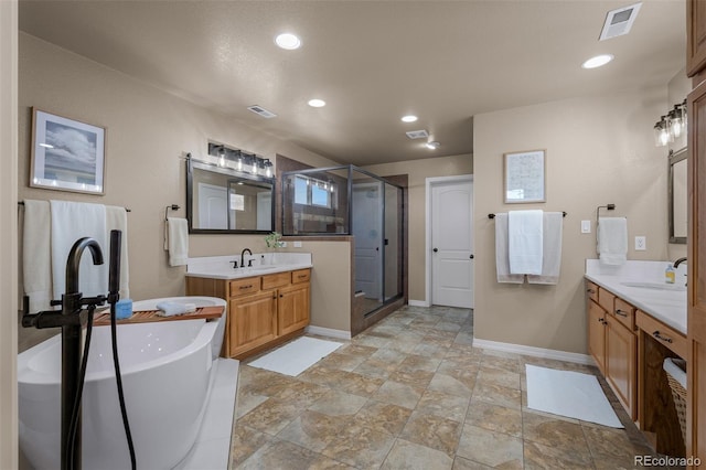 19735 Knights Xing, Monument, CO 80132 - bathroom featuring a shower stall, two vanities, a freestanding bath, recessed lighting, and stone finish floors