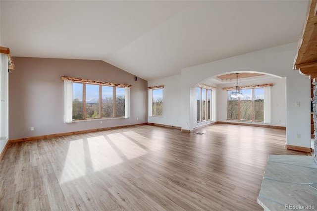 unfurnished living room with arched walkways, a chandelier, light wood-style flooring, baseboards, and vaulted ceiling