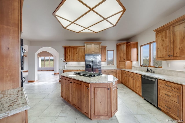 kitchen featuring gas cooktop, a kitchen island, dishwasher, a sink, and stainless steel fridge