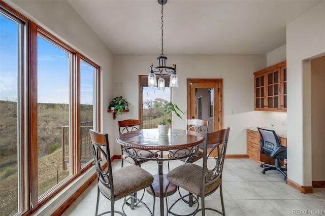 dining room featuring light tile patterned flooring, baseboards, and an inviting chandelier