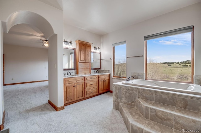 bathroom featuring double vanity, a ceiling fan, a sink, and a garden tub