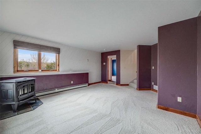 interior space with stairway, baseboards, a wood stove, and a baseboard radiator