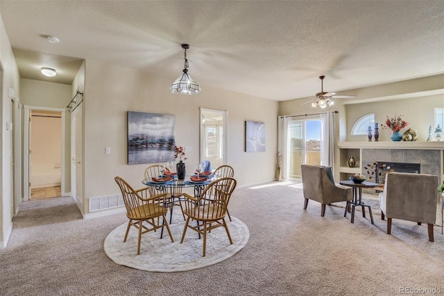1447 Madison Ridge Hts, Colorado Springs, CO 80904 - carpeted dining space with a tile fireplace, a ceiling fan, a textured ceiling, and baseboards