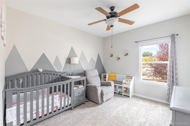 carpeted bedroom with a nursery area and ceiling fan