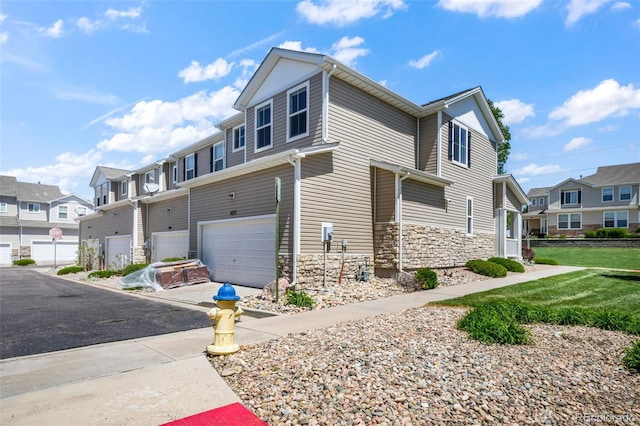 view of property exterior with a residential view, stone siding, a garage, and driveway