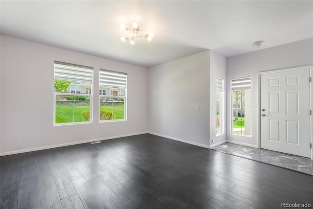 entryway featuring healthy amount of natural light, baseboards, and a chandelier