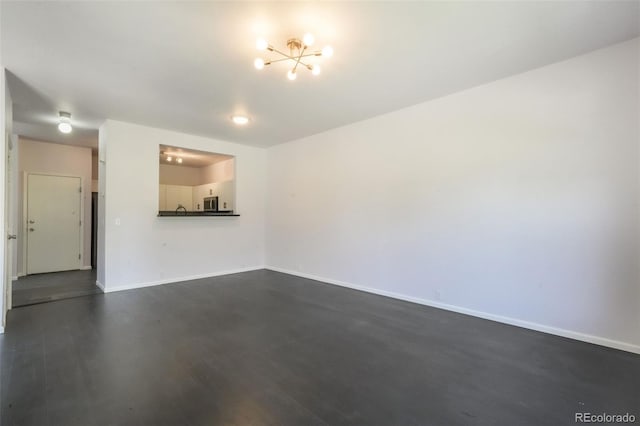 unfurnished living room featuring dark wood-type flooring, a chandelier, and baseboards