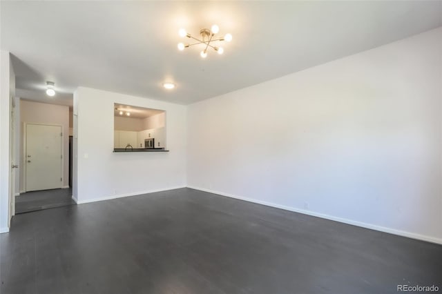 unfurnished living room featuring a chandelier, baseboards, and dark wood-style floors