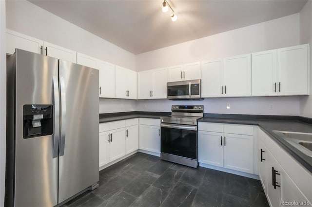 kitchen featuring appliances with stainless steel finishes, dark countertops, and white cabinetry