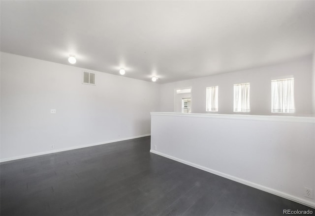 empty room with dark wood-style floors and baseboards