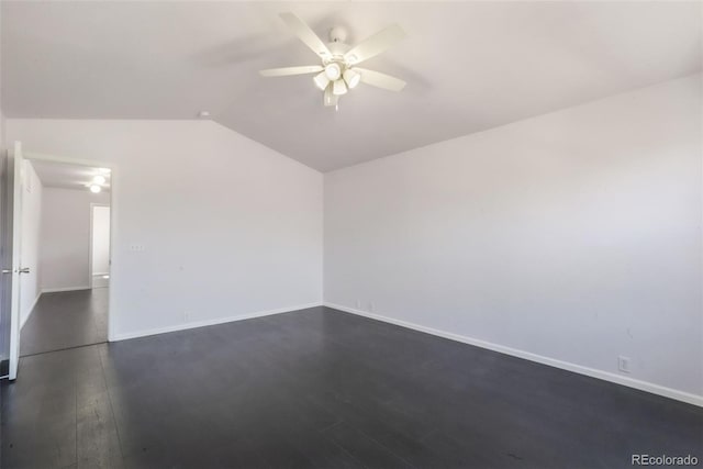 empty room with dark wood-type flooring, vaulted ceiling, a ceiling fan, and baseboards