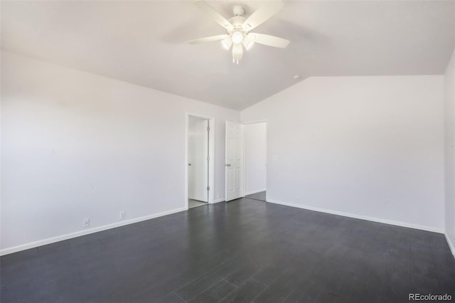 spare room with a ceiling fan, vaulted ceiling, dark wood-type flooring, and baseboards