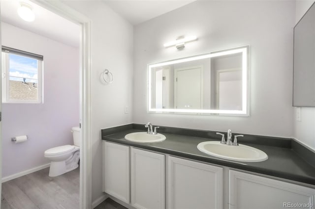 bathroom with toilet, wood finished floors, and double vanity