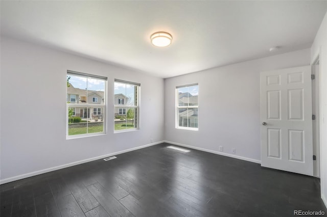 spare room featuring baseboards and dark wood finished floors