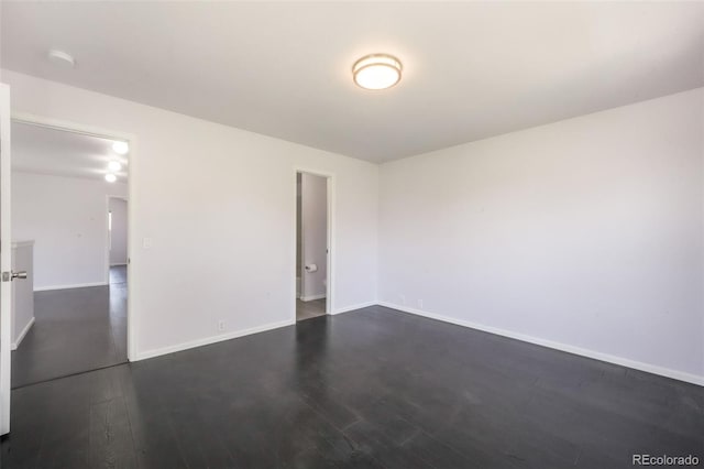 spare room featuring dark wood-style floors, baseboards, and a smoke detector