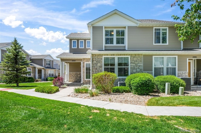 view of front of property featuring stone siding, a front yard, covered porch, and central air condition unit
