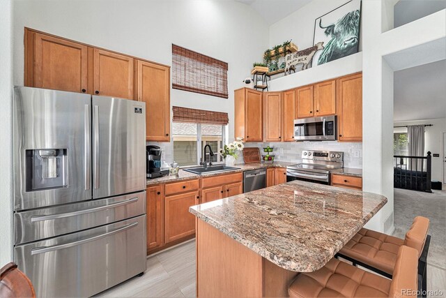 15776 E 107th Way, Commerce City, CO 80022 - kitchen with appliances with stainless steel finishes, a towering ceiling, a sink, light stone countertops, and backsplash