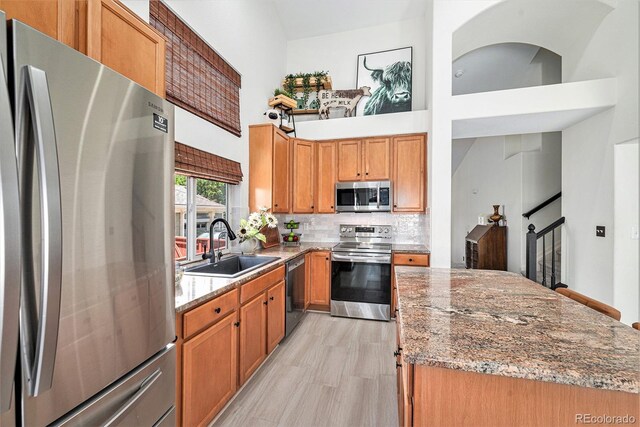 15776 E 107th Way, Commerce City, CO 80022 - kitchen with appliances with stainless steel finishes, a sink, backsplash, a towering ceiling, and light stone counters