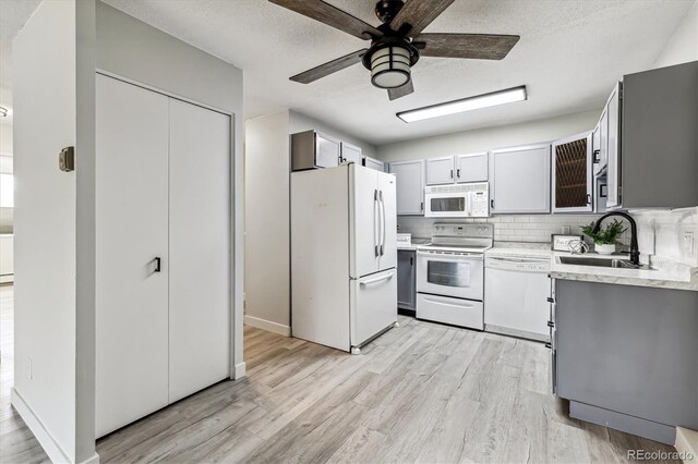 kitchen featuring light hardwood / wood-style flooring, tasteful backsplash, white appliances, ceiling fan, and sink