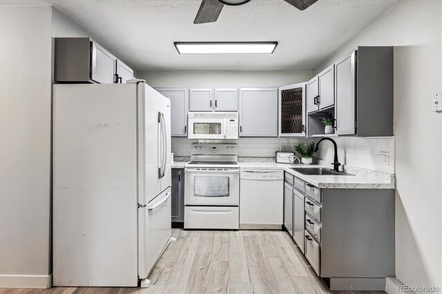 kitchen featuring sink, light hardwood / wood-style flooring, white appliances, and gray cabinetry