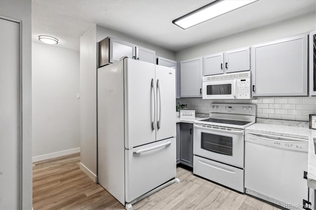 kitchen with white appliances, tasteful backsplash, light wood finished floors, light countertops, and gray cabinetry