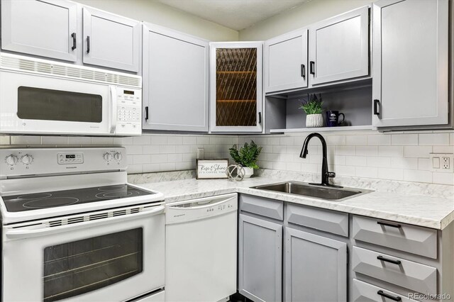 kitchen with sink, gray cabinets, white appliances, and backsplash