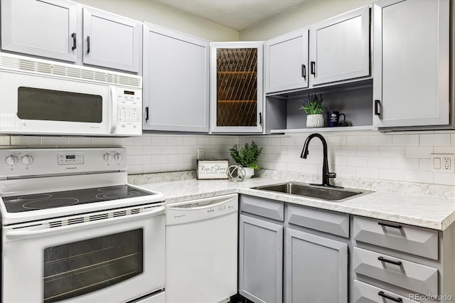 kitchen with white appliances, decorative backsplash, light stone counters, open shelves, and a sink