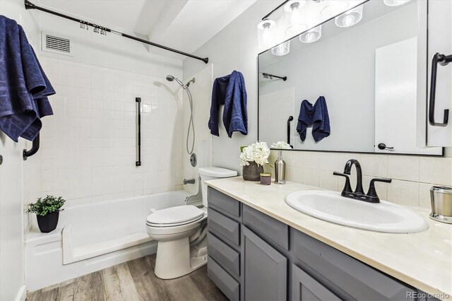 full bathroom featuring vanity, wood-type flooring, tile walls, toilet, and backsplash