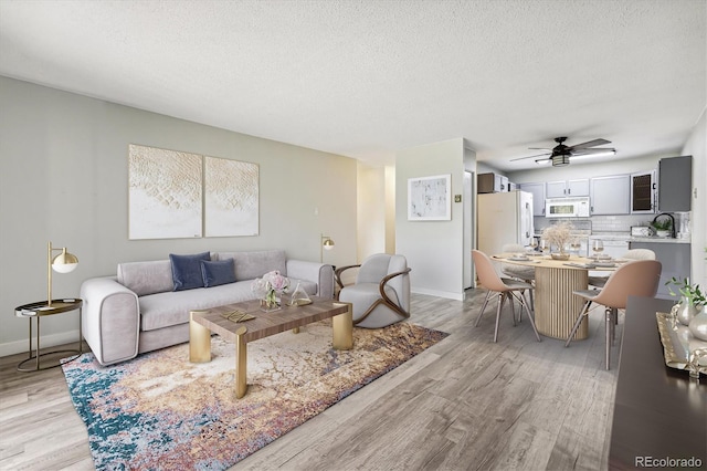 living room featuring light hardwood / wood-style floors, a textured ceiling, and ceiling fan