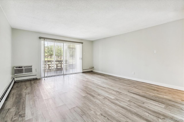 spare room with an AC wall unit, a textured ceiling, a baseboard heating unit, and light hardwood / wood-style floors