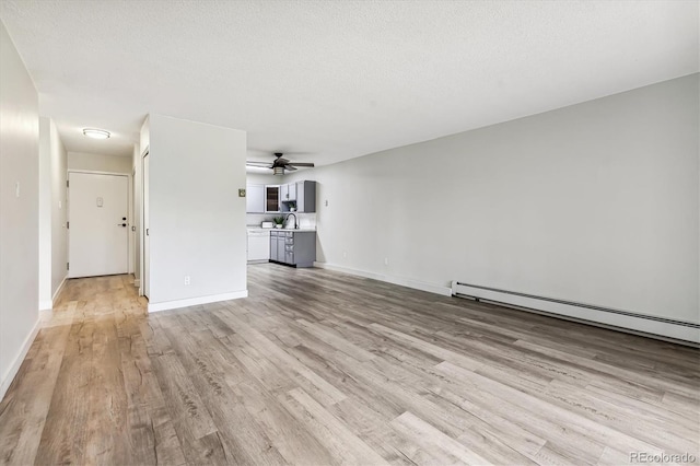 unfurnished living room with light wood finished floors, a baseboard radiator, baseboards, and a textured ceiling