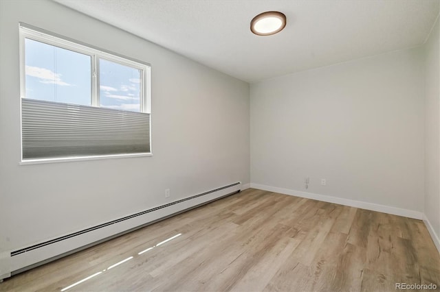 unfurnished room featuring a baseboard radiator, baseboards, and light wood finished floors